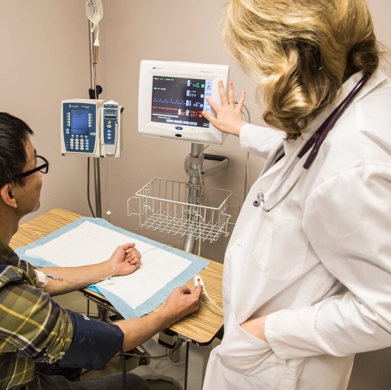 Lab technician viewing readout on screen with patient seated alongside